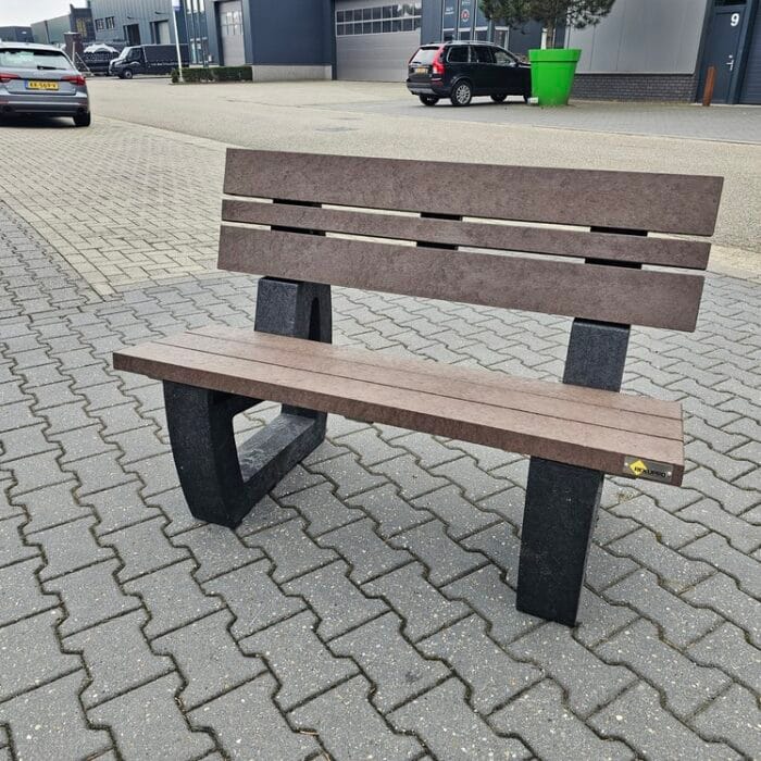 Bruin kunststof bankje met rugleuning en zwart onderstel, geplaatst op een bestrate buitenlocatie voor een bedrijfspand